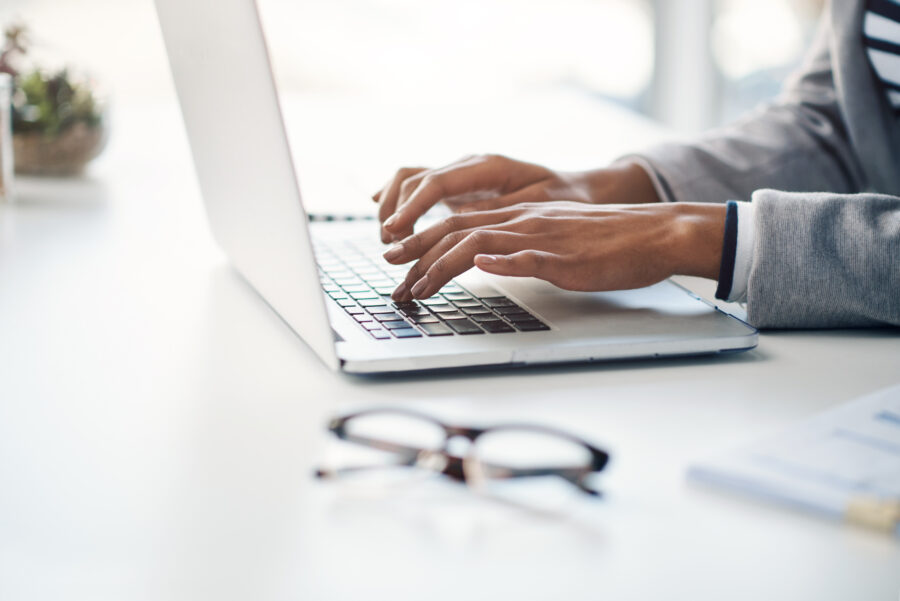 Office, typing and hands of woman at laptop for research, business review or online report at agency. Budget, planning and consultant at desk with computer, networking and financial risk management